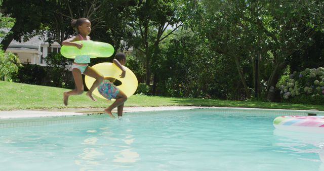 Children Jumping into Sunlit Pool with Inflatable Rings - Download Free Stock Images Pikwizard.com