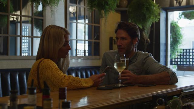 Couple enjoying a relaxing date in a cozy bar setting, sipping beer and wine. Possible use for travel brochures, lifestyle blogs, advertisements for hospitality or drinks industries, highlighting social or leisure activities, relationships, and modern lifestyle.