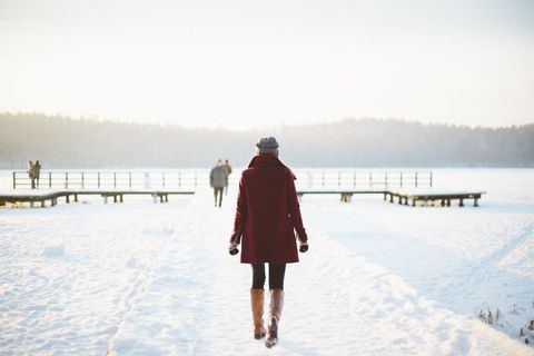 Person Walking on Snow-Covered Pier in Winter Landscape