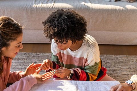 Multicultural women painting nails during cozy sunlit home manicure session