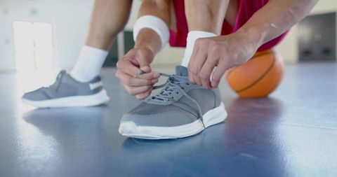 Athlete Tying Sneaker Laces on Indoor Basketball Court