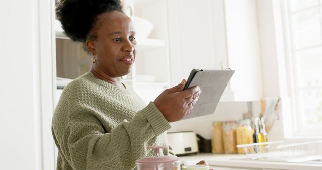 Mature woman using digital tablet in kitchen - Download Free Stock Images Pikwizard.com