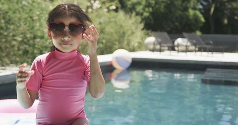 Joyful Girl in Heart Sunglasses by Pool