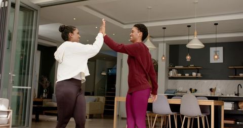 Diverse Female Friends High-Fiving in Modern Minimalist Home