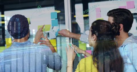 Team brainstorming on glass board with colorful post-its and data visualization overlay