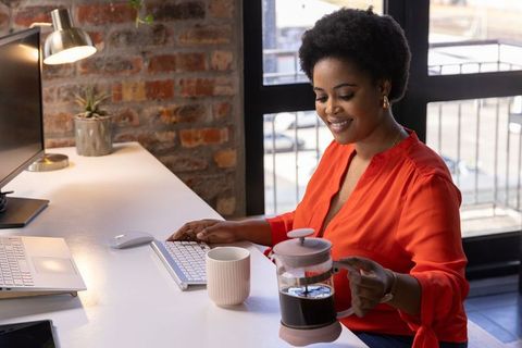 African American Woman Enjoying Coffee in Modern Workspace