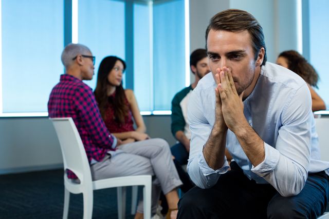 Man crying while creative business team in background at office