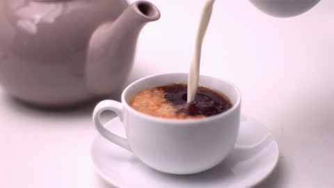 Milk Gently Flowing into Cup of Tea in Slow Motion Close-Up
