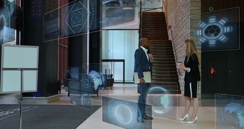 Business colleagues talking in modern atrium with holographic interfaces and glass staircase