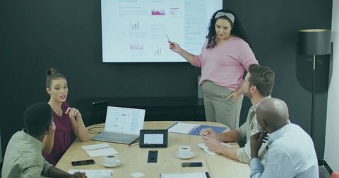 Diverse Team in Meeting Analyzing Presentation on Display Screen