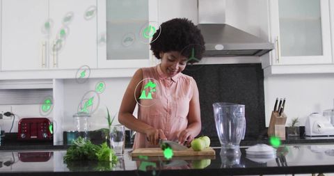Woman cutting apples on kitchen island with augmented reality health icons