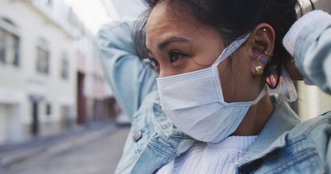 Woman Putting On Protective Face Mask in Urban Street