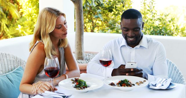 Man ignoring bored woman while using mobile phone in restaurant