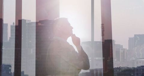 Businessman reflecting on skyline in highrise office with glass panels
