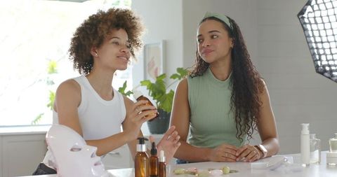 African american influencers demonstrating skincare routine with led mask and serum