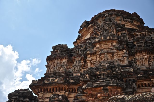 This image showcases an ancient temple structure with detailed carvings against a clear blue sky. The intricate stone architecture highlights the cultural and historical significance of the site, making it an excellent visual for travel blogs, cultural articles, educational material about historical architectures and heritage preservation campaigns.