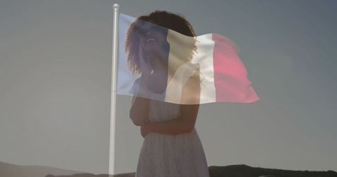 Elegant Woman Gazing Upward at French Flag in Serene Landscape