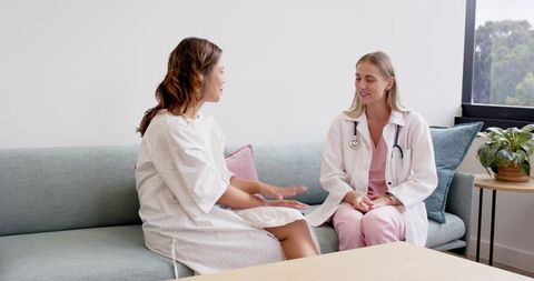 Patient discussing health with doctor on clinic couch showing empathy and communication
