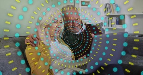 Senior couple relaxing on sofa using laptop with teal dotted concentric overlay
