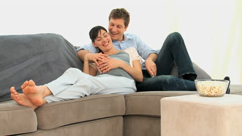 Expectant Couple Relaxing on Sofa with Popcorn