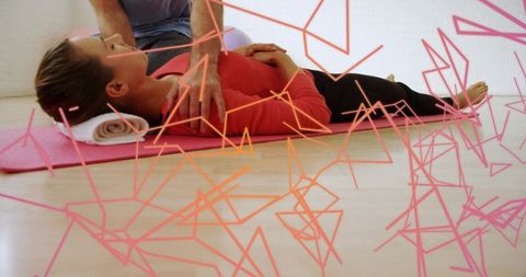 Client receiving therapist-assisted stretch on pink mat with geometric overlay