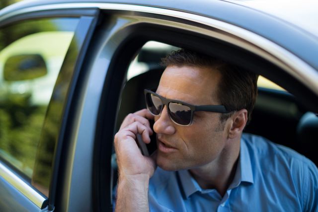 Close up of young man talking on phone while driving car