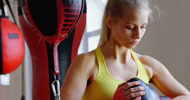 Female Boxer Wrapping Hands in Gym Near Punching Bags - Download Free Stock Images Pikwizard.com