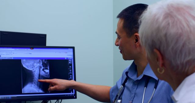 Doctor showing senior patient an X-ray image on a computer monitor. Useful for concepts related to healthcare, patient care, medical consultations, doctor-patient relationships, technological advancements in medicine, and senior health check-ups.