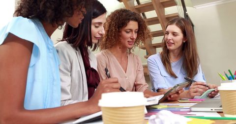 Focused Women Collaborating with Documents and Tablet in Office