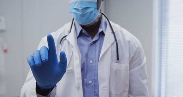 Midsection of african american male doctor wearing face mask and surgical gloves - Download Free Stock Photos Pikwizard.com