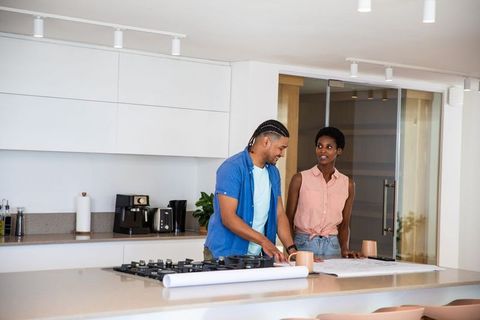Couple Reviewing Blueprints in Modern Kitchen Setting