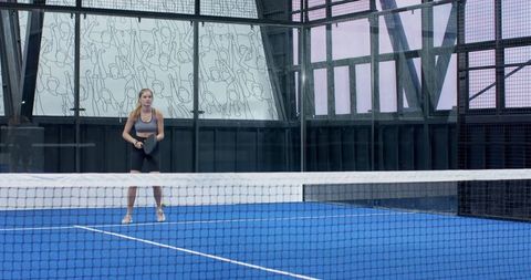 Female athlete playing padel on modern indoor court