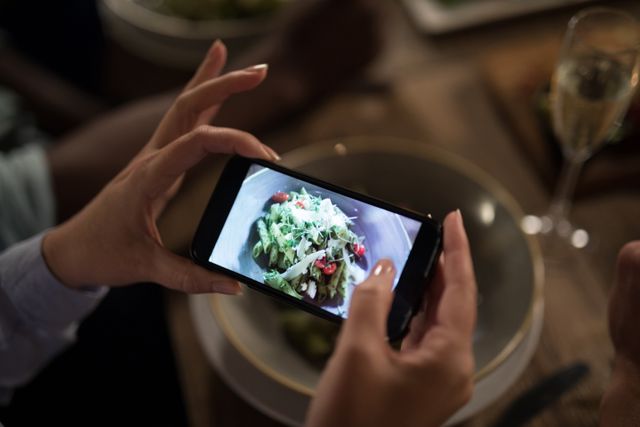Woman taking photo of meal with mobile phone in restaurant