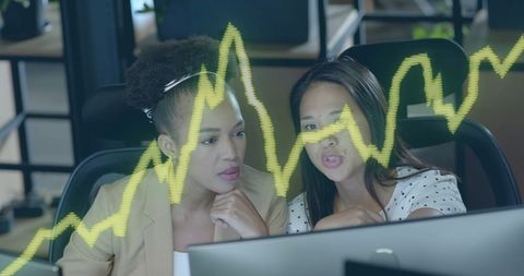 Diverse Businesswomen Analyzing Financial Data Trends in Modern Office