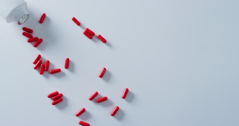 Red Pills Spilled on White Surface with Copy Space