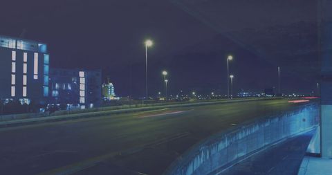 Night City Highway with Buildings Illuminated Against Dark Sky