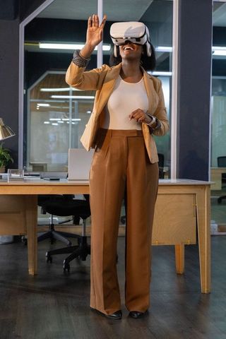 Businesswoman exploring virtual reality headset in modern office workspace for tech demo