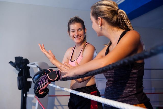 Female boxer and coach interacting in boxing ring, discussing training techniques and strategies. Ideal for use in fitness blogs, sports training websites, gym advertisements, and motivational content.