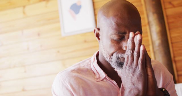 Senior african american man in log cabin praying with eyes closed. Log cabin and lifestyle concept.