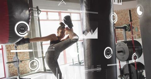 Female kickboxer delivering high roundhouse kick to heavy bag with hud fitness analytics