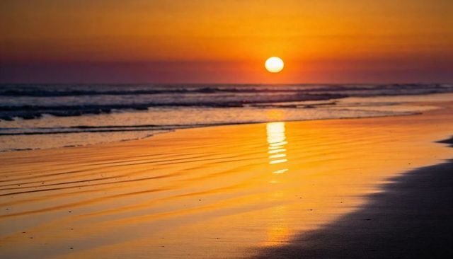 Casting sun lowering toward horizon, bathing wet sand with golden reflection and waves