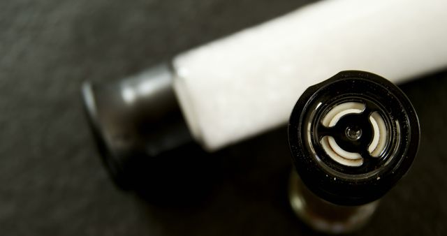 A close-up view of an open tube of cream or ointment on a dark surface, with copy space. The focus on the tube's nozzle reveals the swirled product inside, indicating it's ready for use.