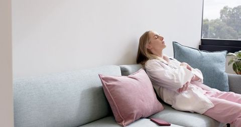 Female healthcare worker reclining on sofa during break in calm staff lounge