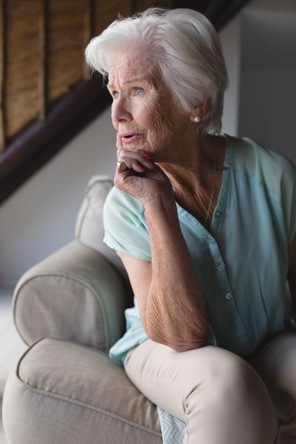 Front view of a thoughtful senior woman relaxing in living room at home