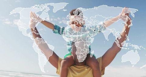 Father carrying son on shoulders at sunny beach with world map overlay for travel bonding