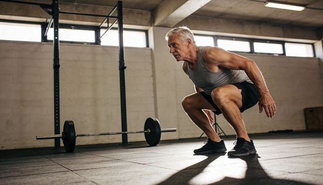 Senior athlete squatting in gym building strength and mobility during weight training