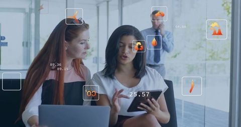Businesswomen collaborating on tablet and laptop with augmented reality interface in office