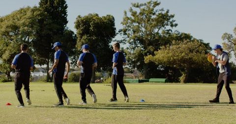 Five players walking across sports field during team training drill holding yellow ball