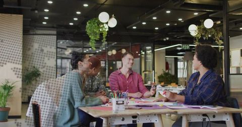 Creative team collaborating around table brainstorming ideas in modern coworking space
