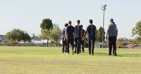 Cricket teammates walking across outfield after training showing teamwork and sportsmanship